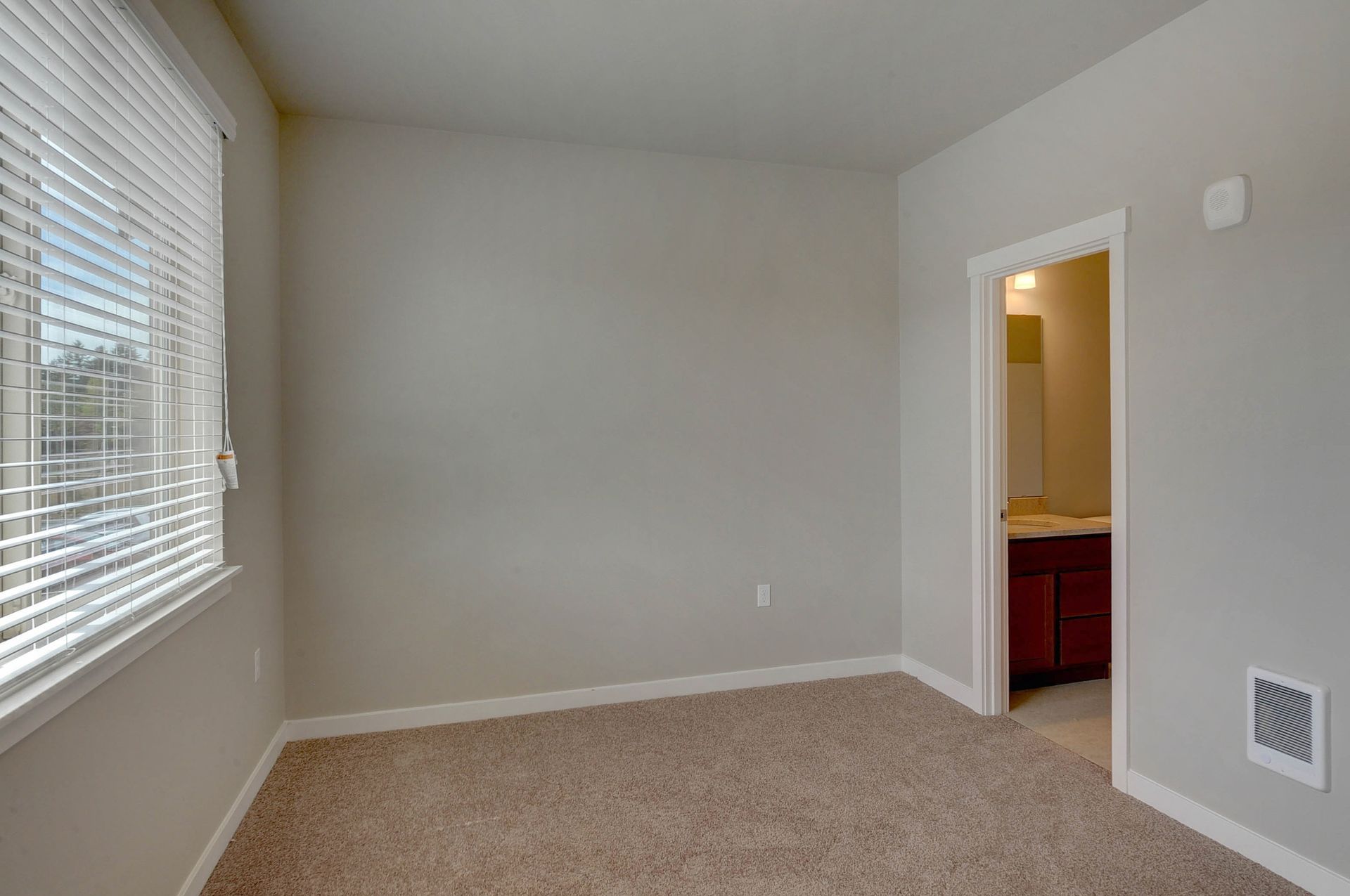 an empty room with a window and a door leading to a bathroom