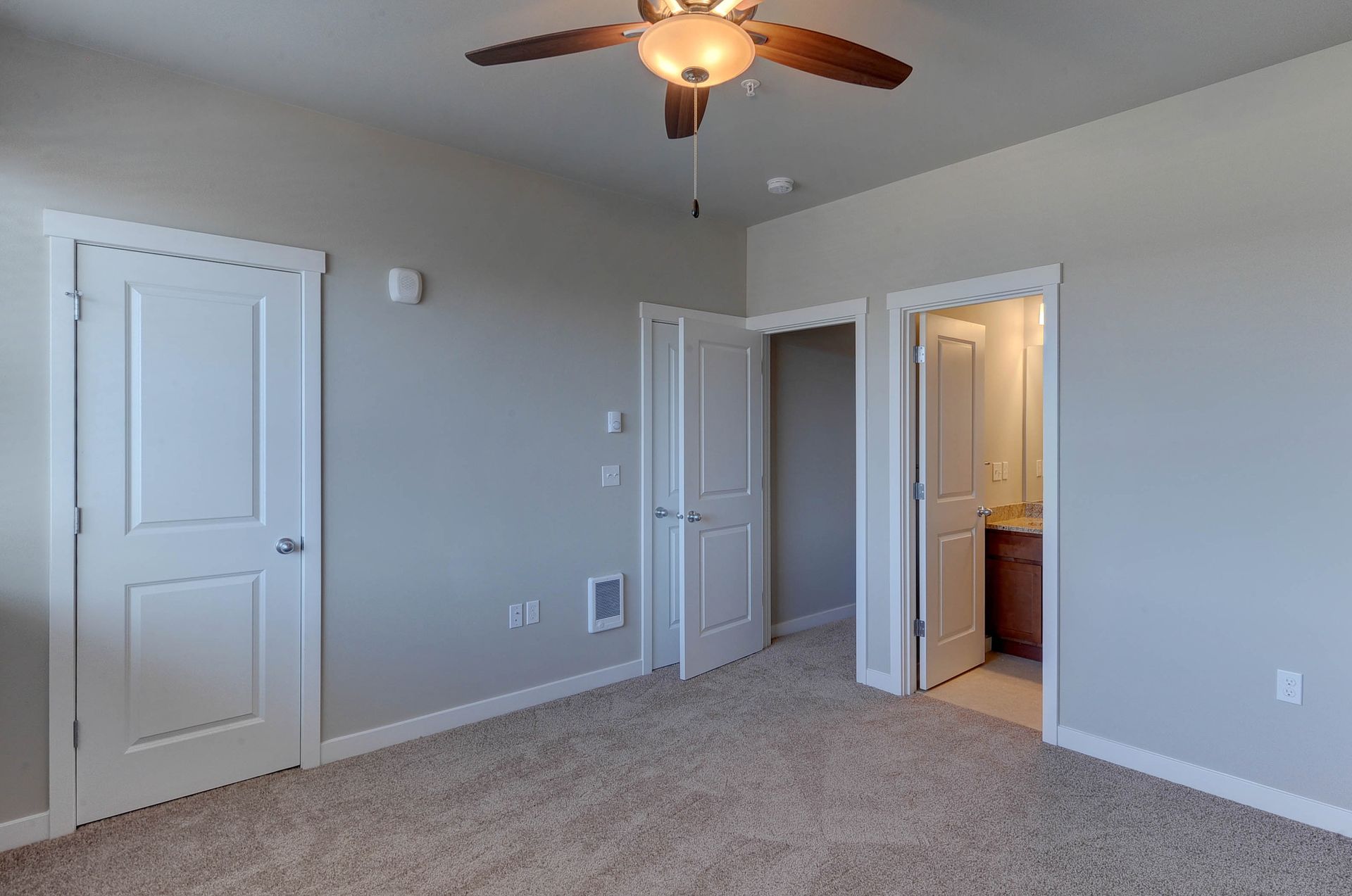 an empty bedroom with a ceiling fan and a bathroom