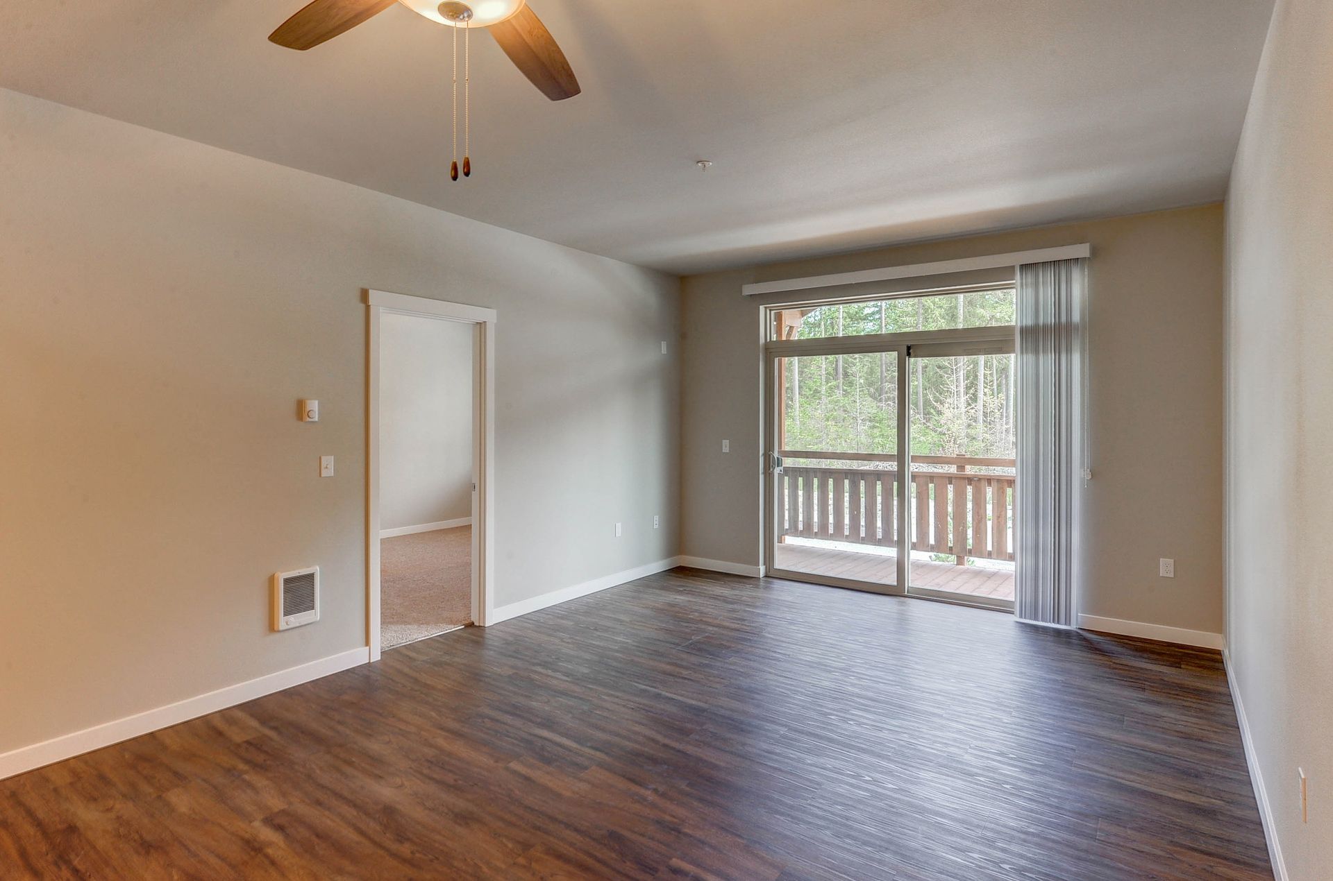 an empty room with a ceiling fan and a sliding glass door