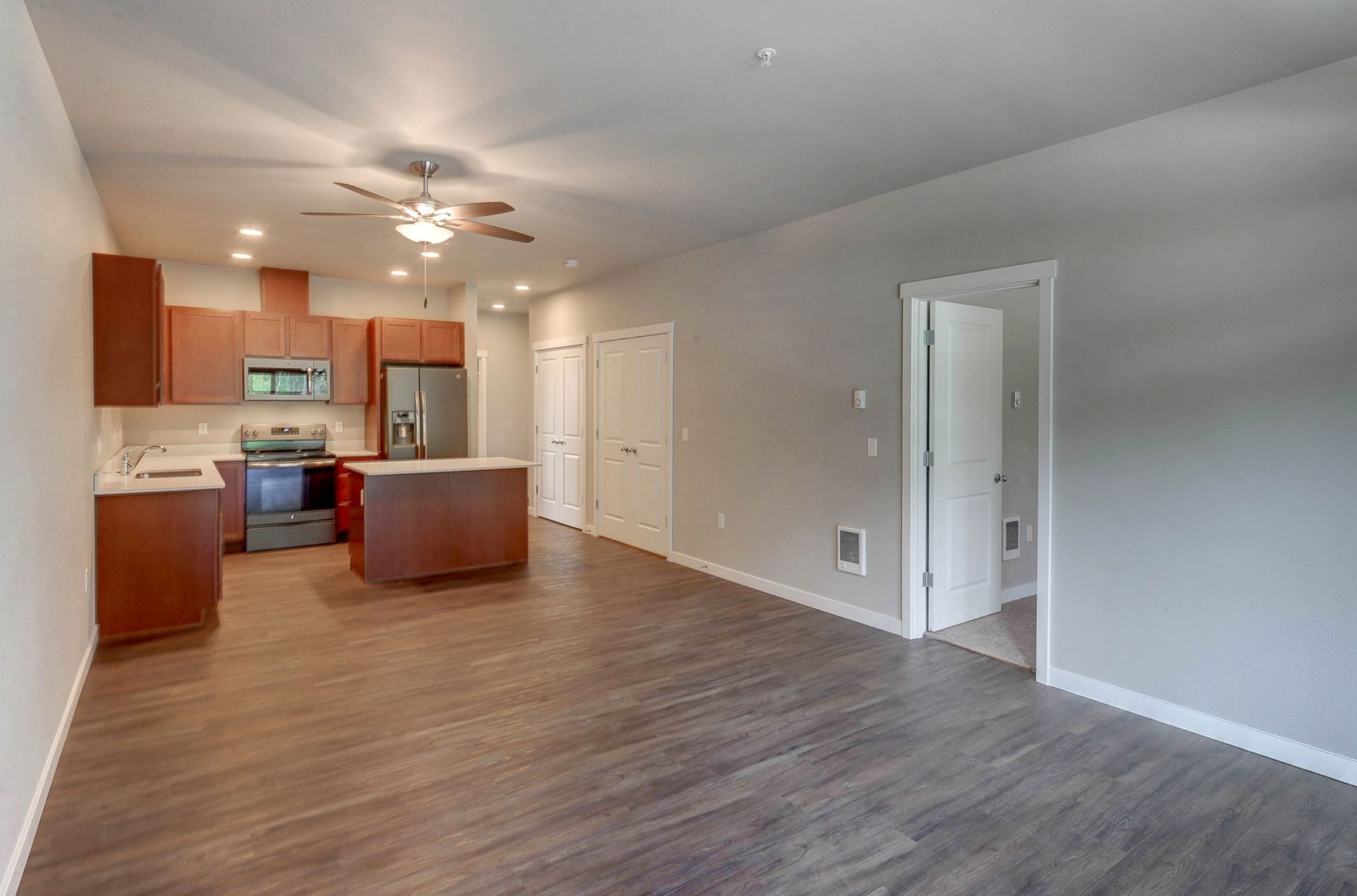 an empty apartment with a kitchen and a ceiling fan