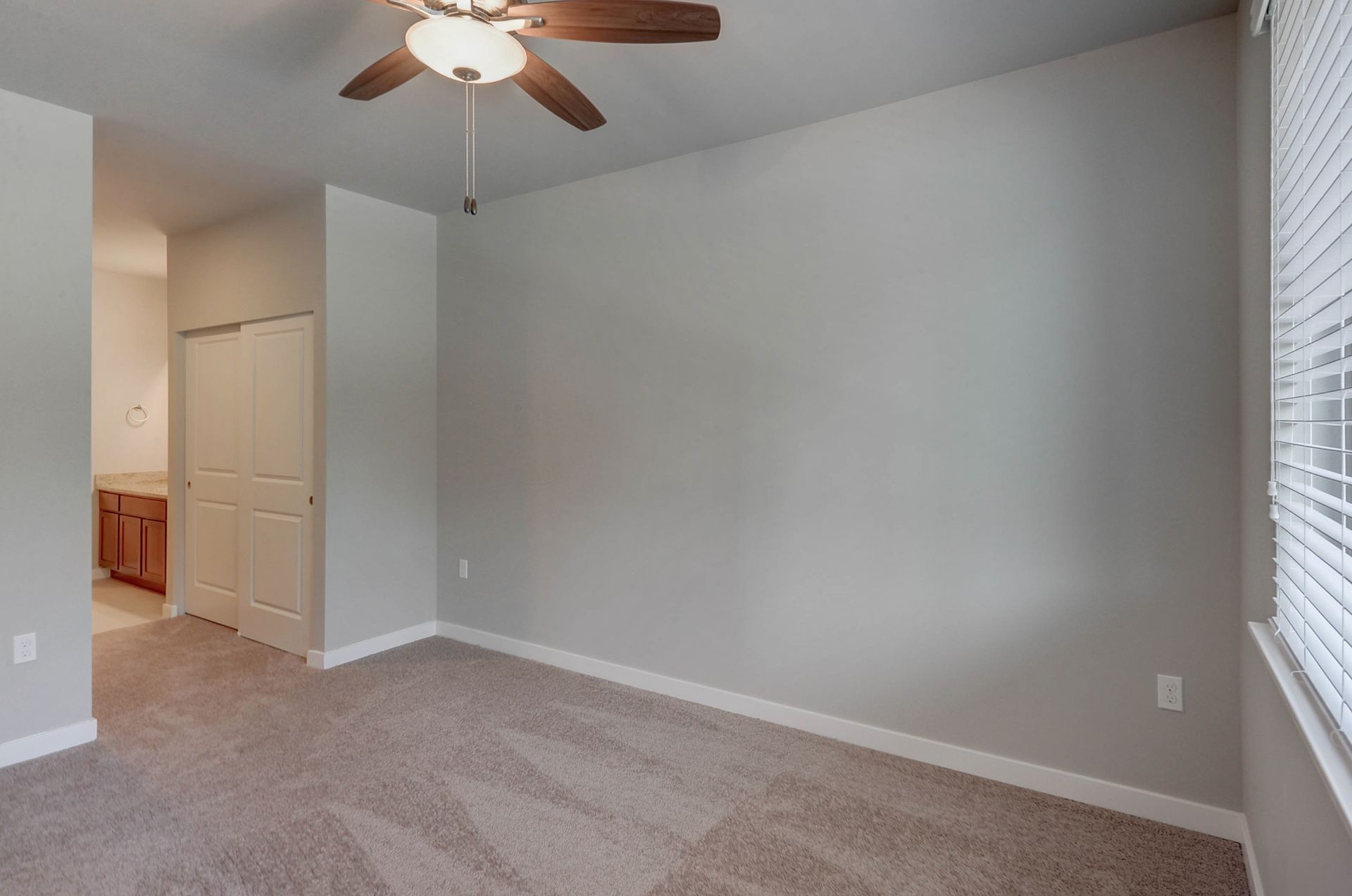 an empty bedroom with a ceiling fan and a window