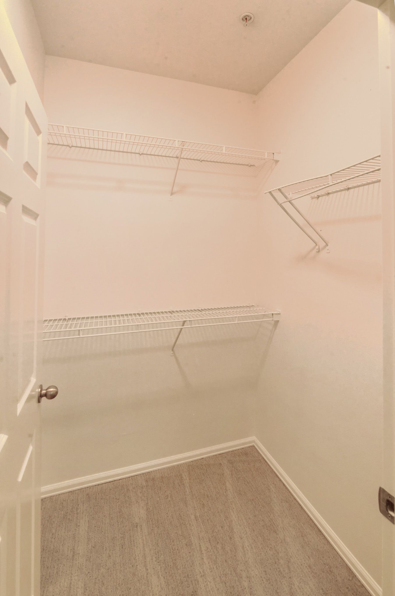 a walk in closet with lots of shelves and a door .