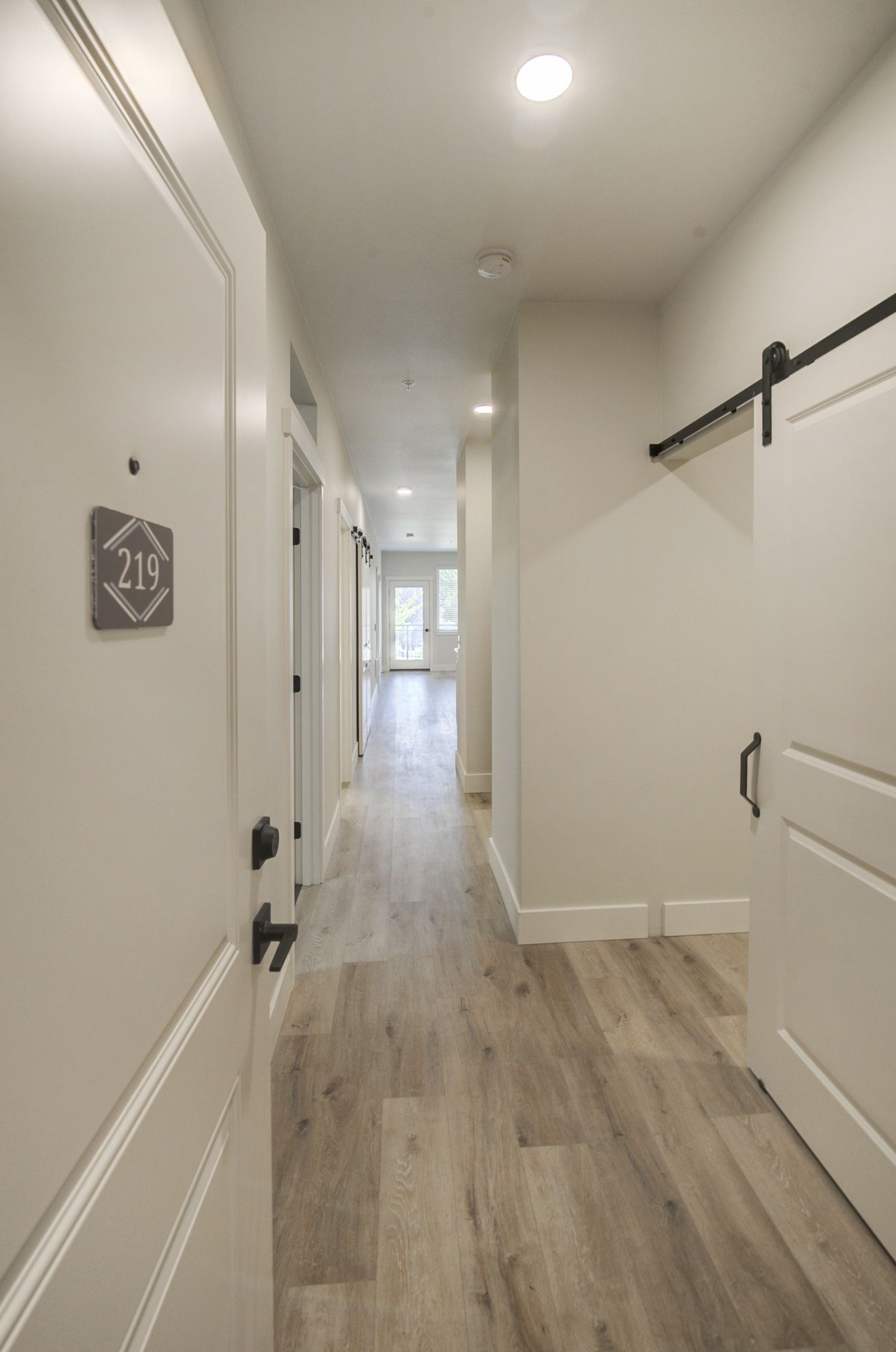 a long hallway with a sliding barn door in a house .