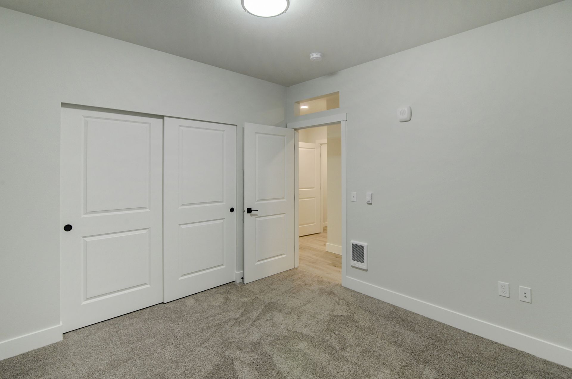 an empty bedroom with a carpeted floor and white walls .