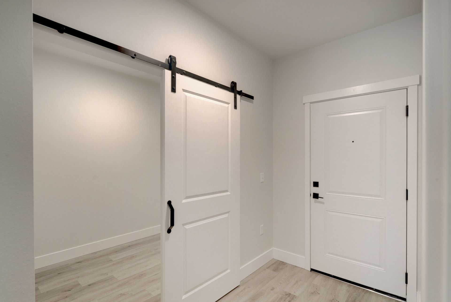 a hallway with a sliding barn door and a white door .
