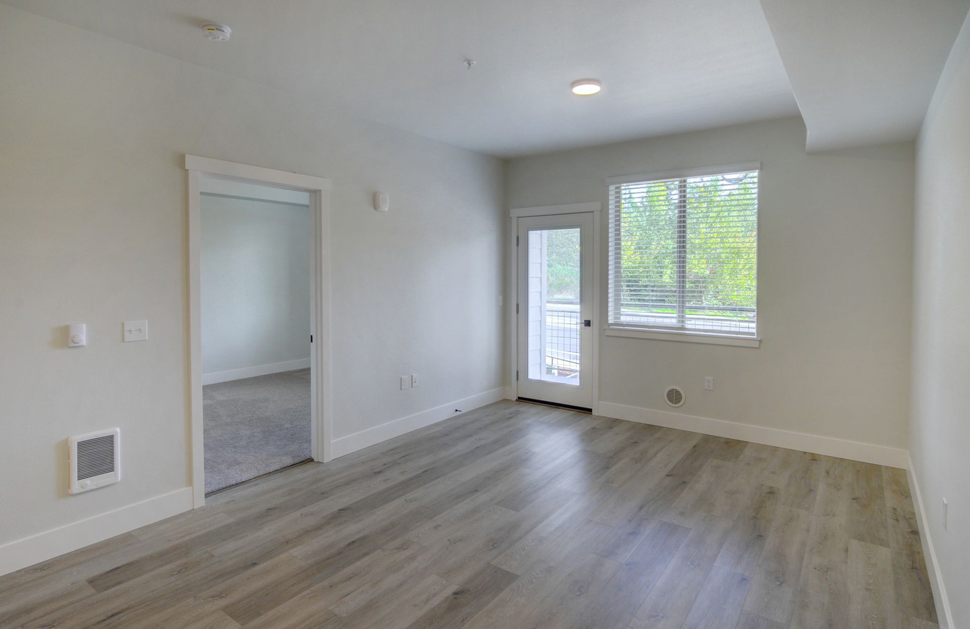 an empty living room with hardwood floors and a sliding glass door .