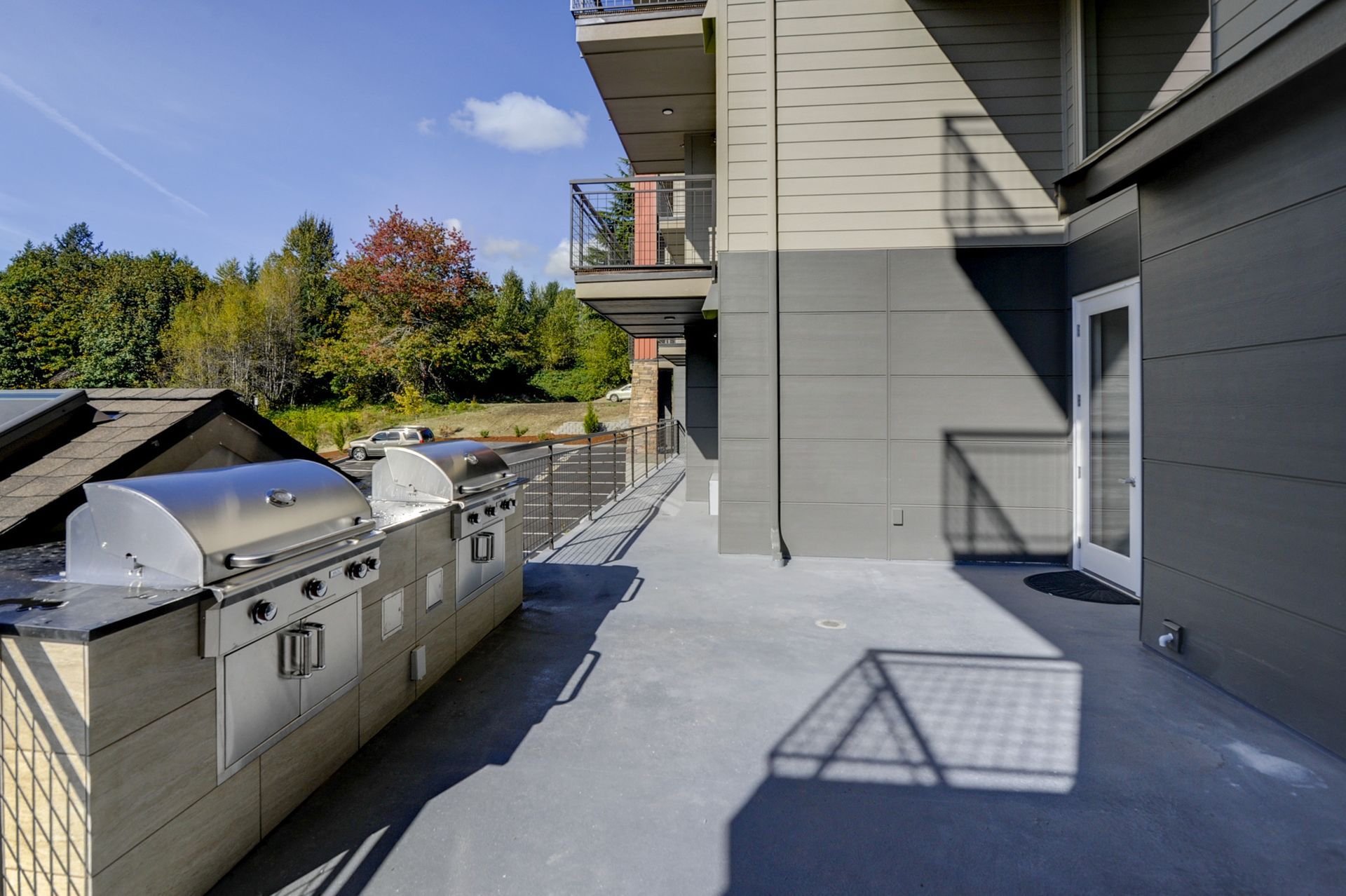 a patio with a grill and a balcony in front of a building