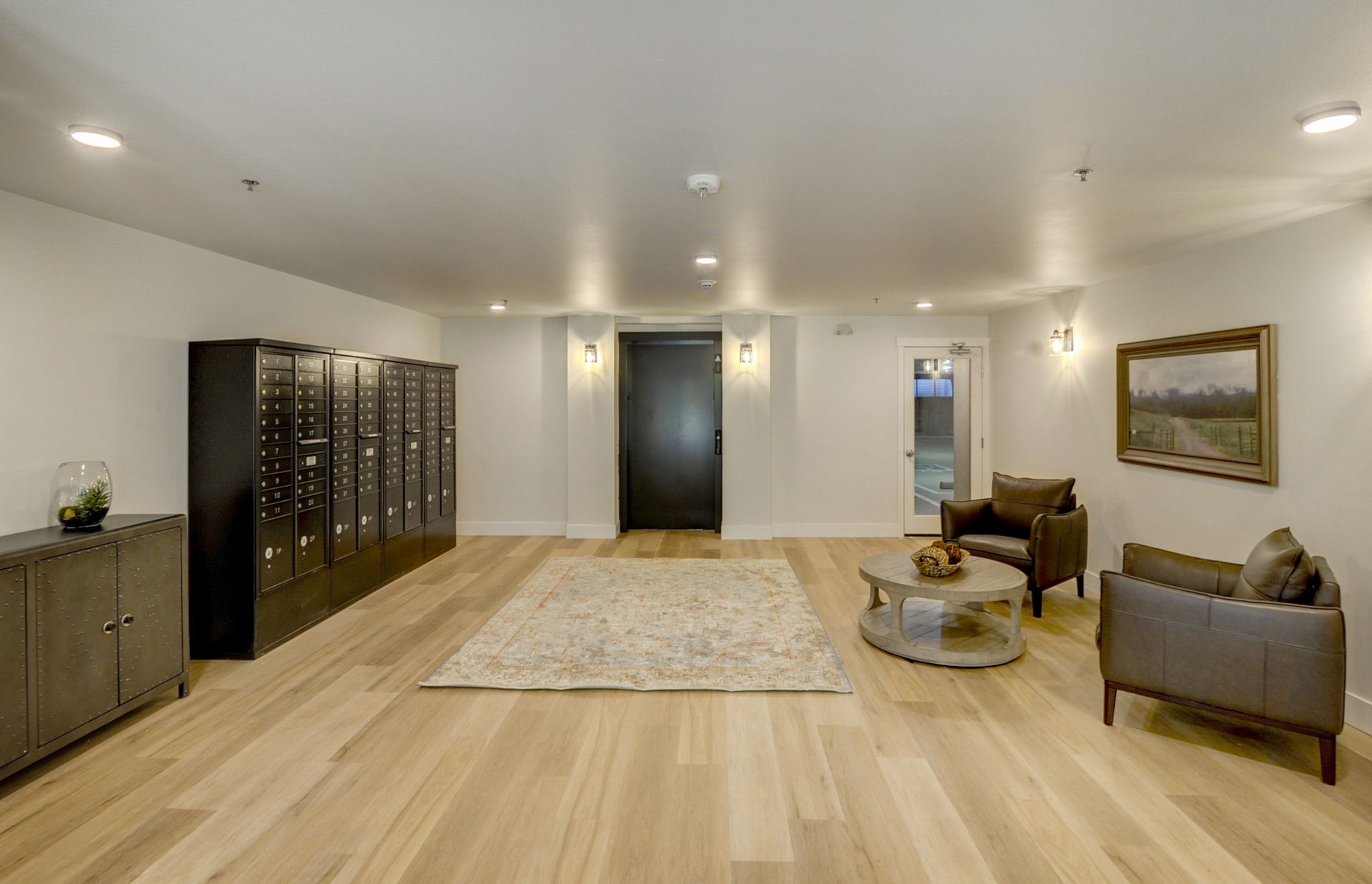 a living room with hardwood floors , chairs , a table and lockers .