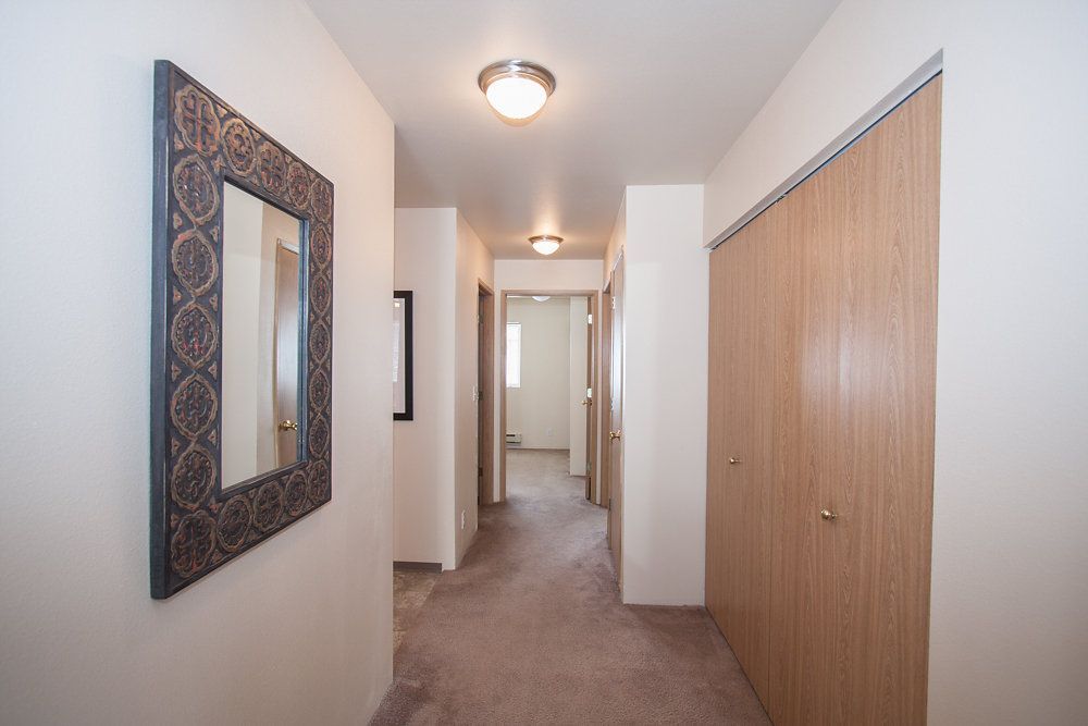 a hallway with wooden doors and a mirror on the wall