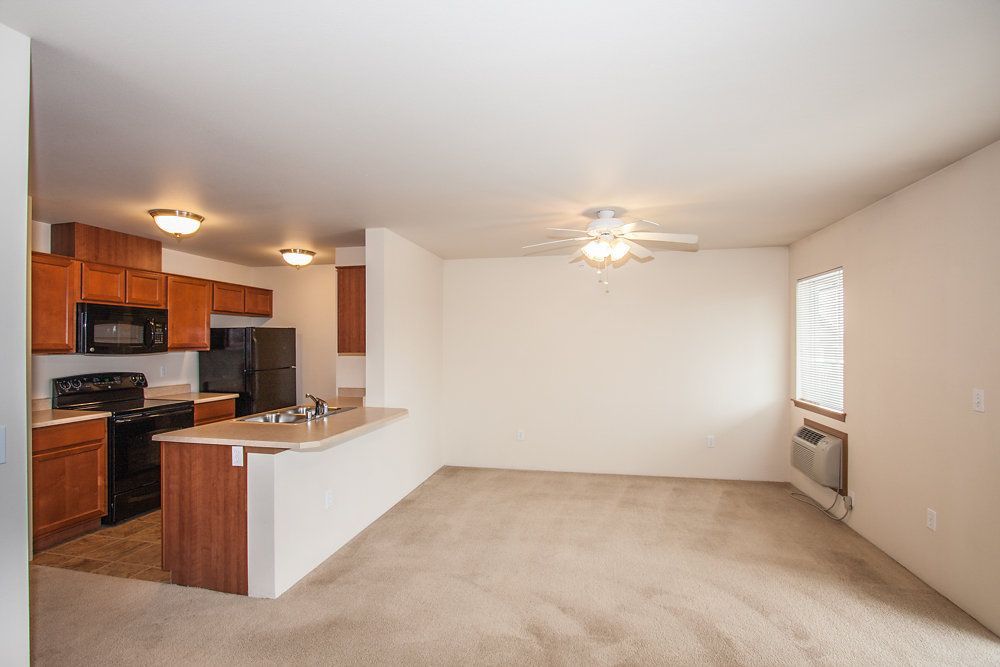 an empty kitchen with a ceiling fan and a window