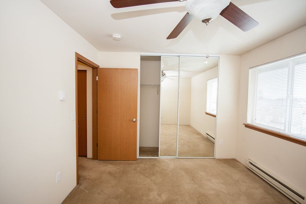 a bedroom with a ceiling fan and a mirror