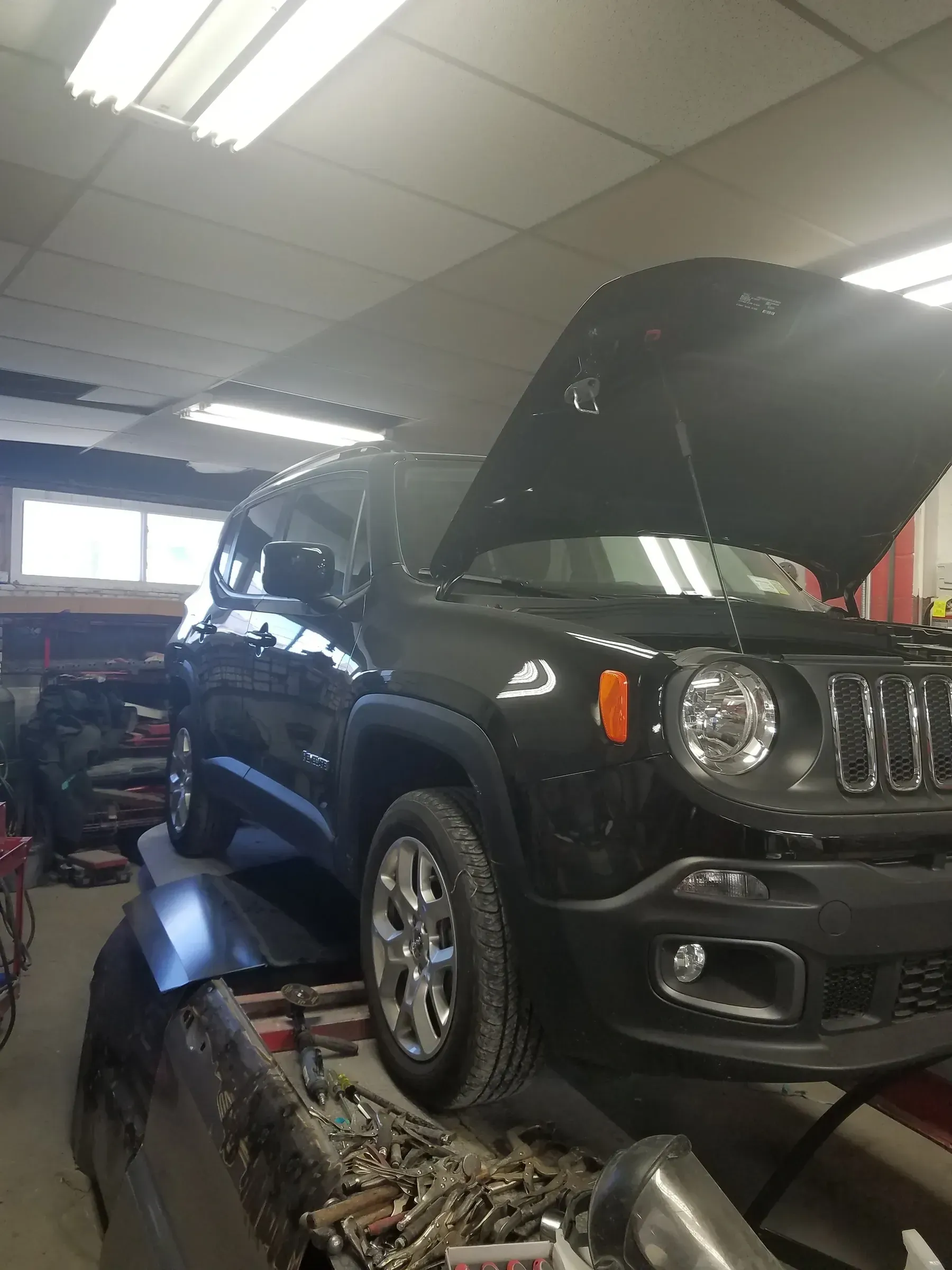 a black jeep is parked in a garage with its hood open .