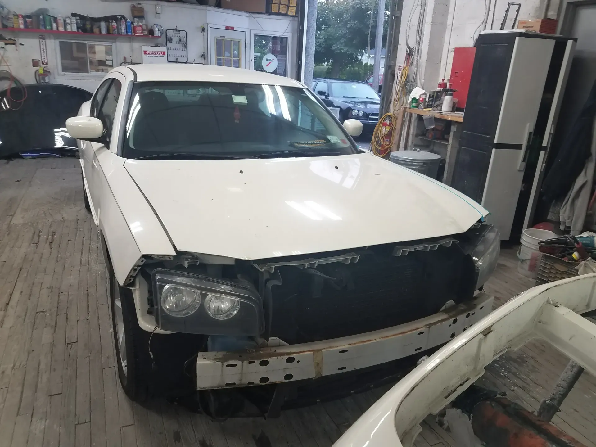 a white car with the hood removed is sitting in a garage .