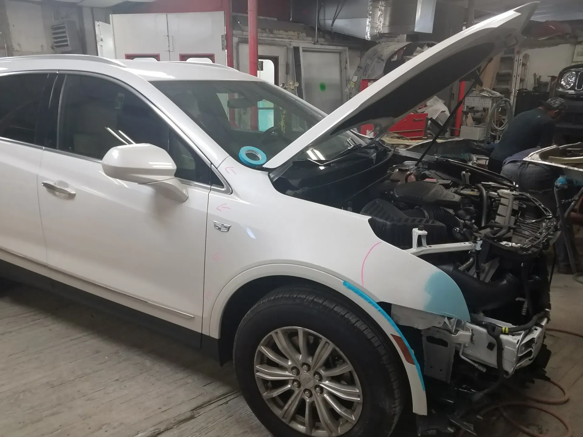 a white car with the hood open is sitting in a garage .