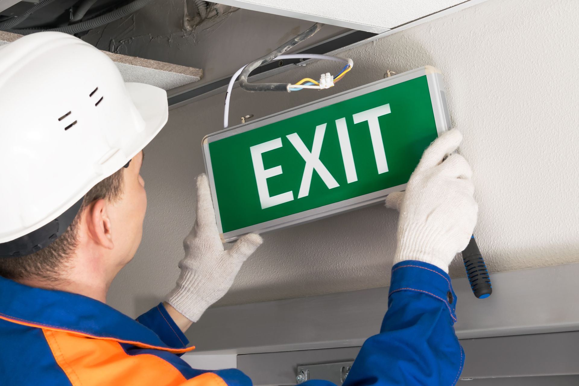 Person in hard hat and gloves installing a green Worker in hard hat installing a green