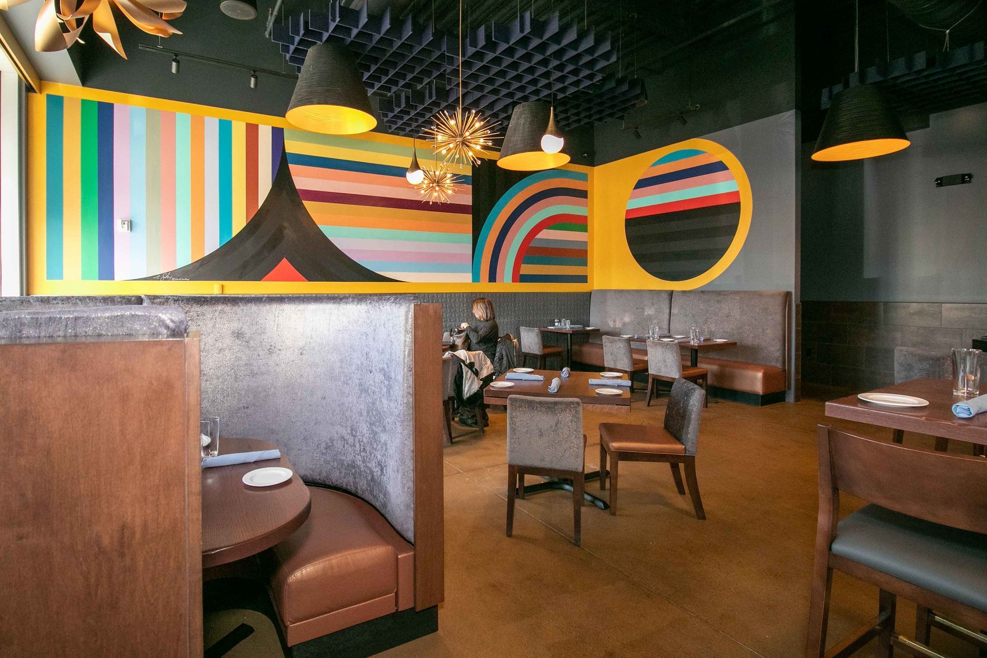 A restaurant with tables and chairs and a painting on the wall.