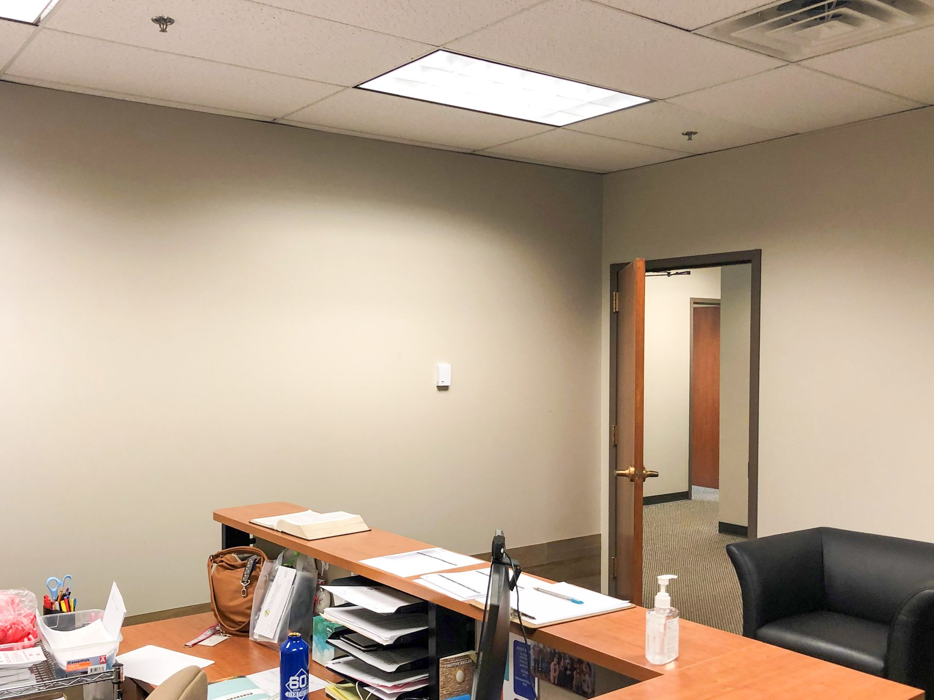 An empty office with a desk , chair , and door.
