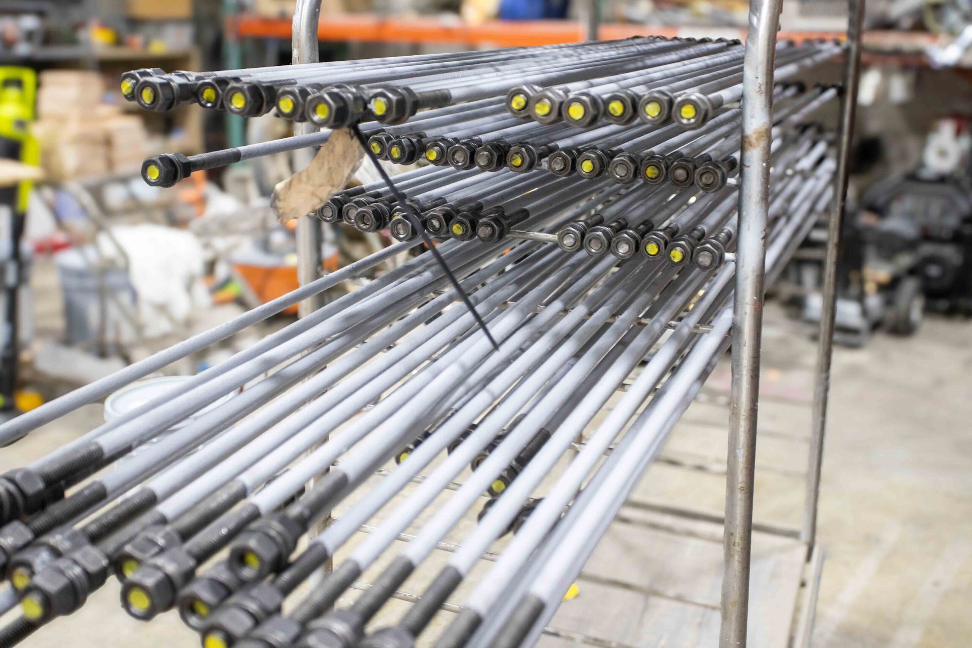 A bunch of metal pipes are stacked on top of each other on a rack in a warehouse.