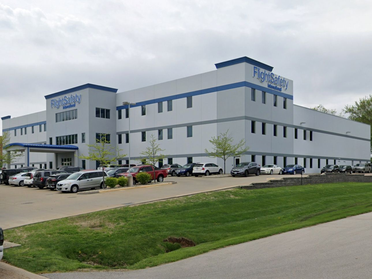 A large white building with a lot of cars parked in front of it.