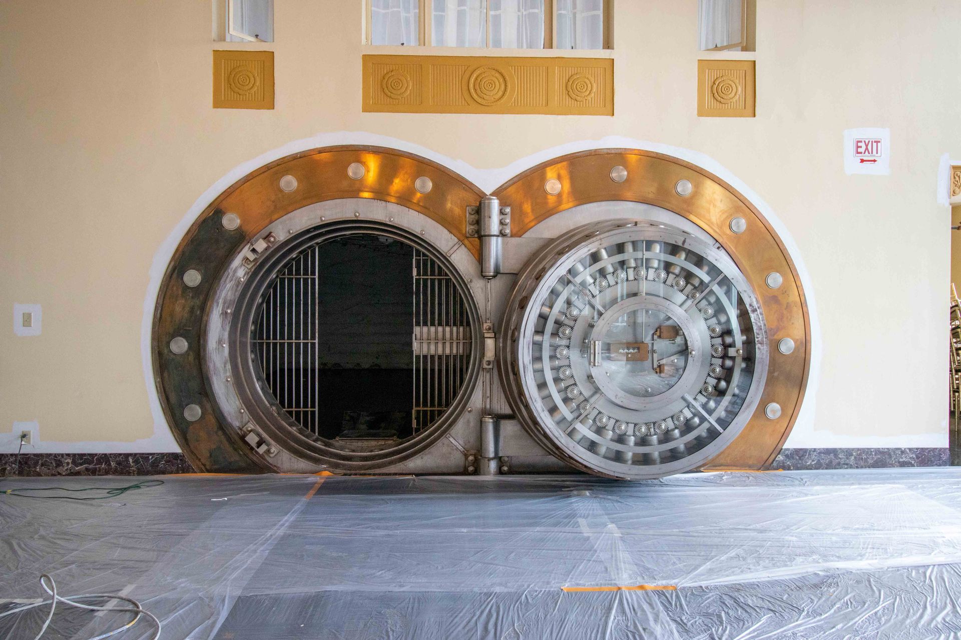 Large circular bank vault door in a beige wall, one side open, in an empty room