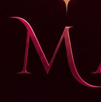 Letra “M” estilizada de color rosa rojizo sobre un fondo oscuro, que brilla con un diseño elegante y reluciente.