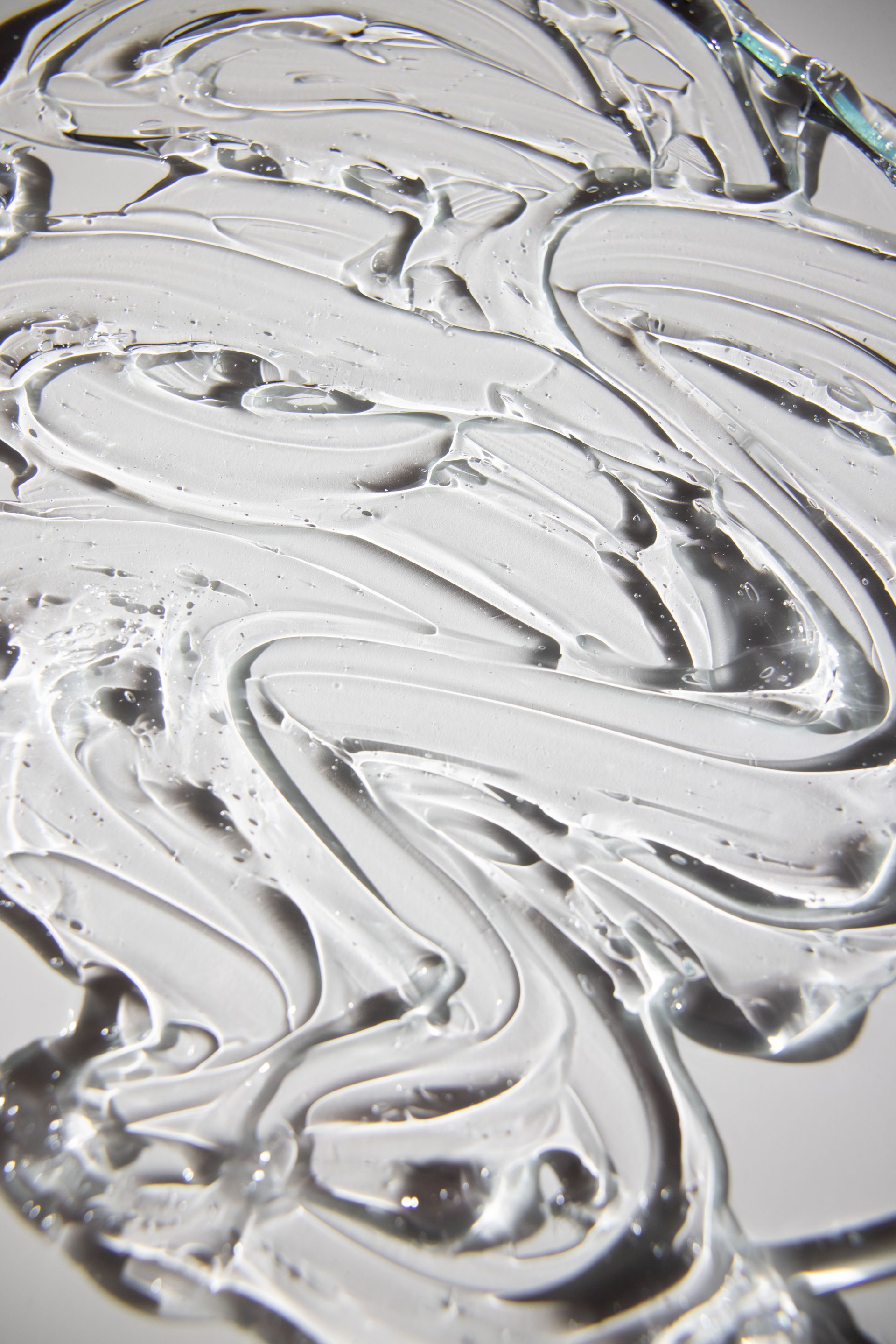 Primer plano abstracto de remolinos blancos brillantes sobre una superficie plateada reflectante.