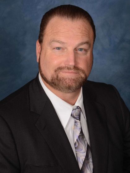 A man in a suit and tie is smiling for the camera