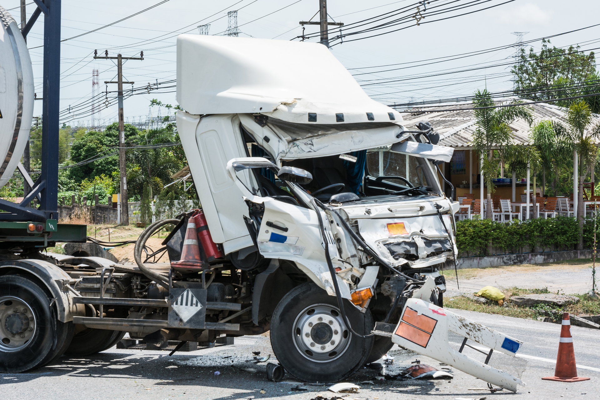 Damaged white semi-truck cab after a collision on a road.