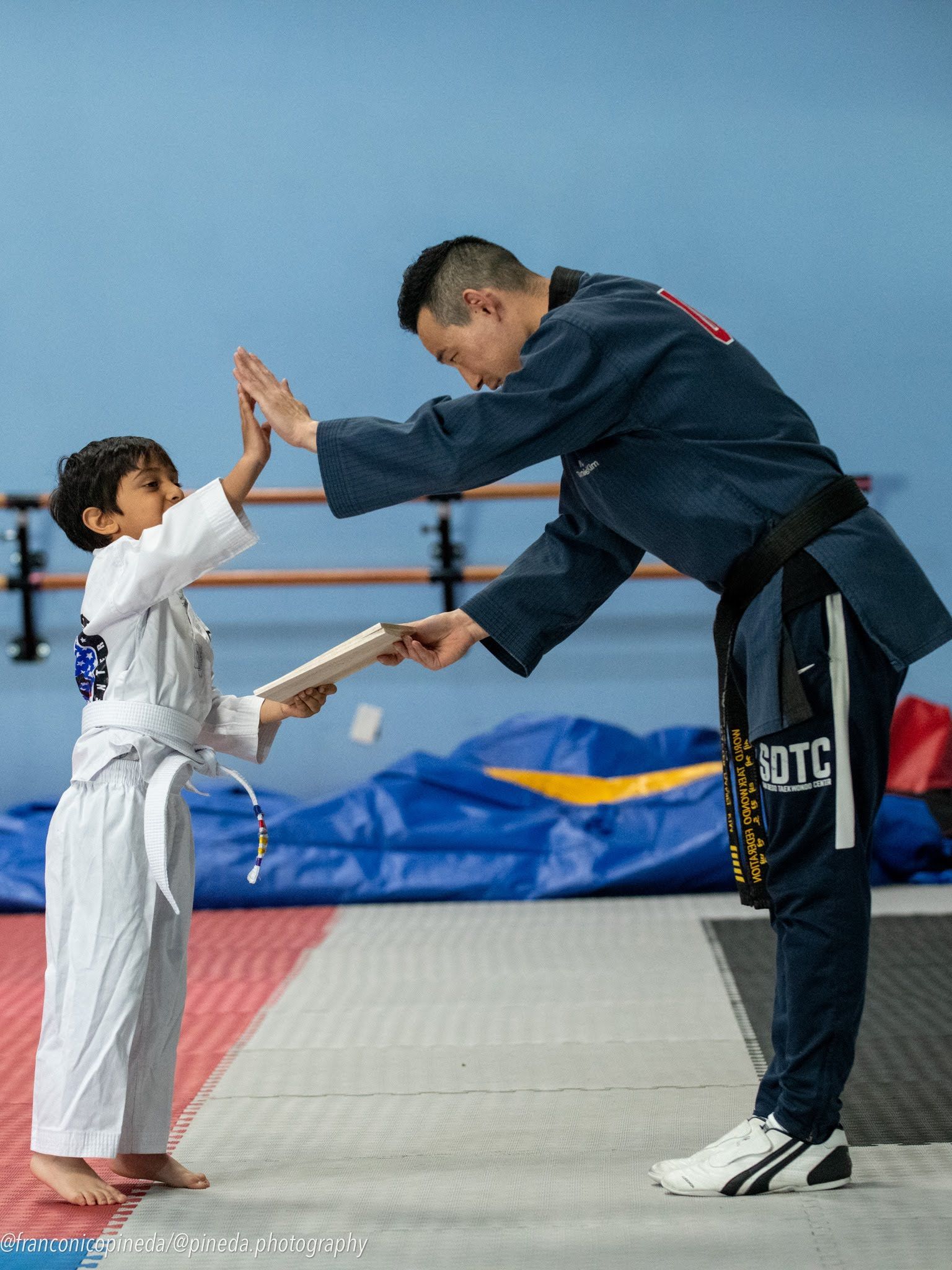 A man is giving a certificate to a young boy in a karate uniform.