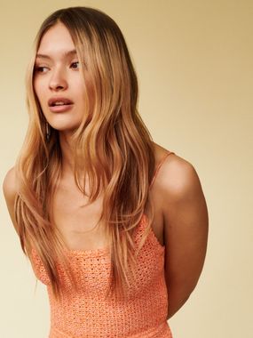 A woman with long hair is wearing an orange dress
