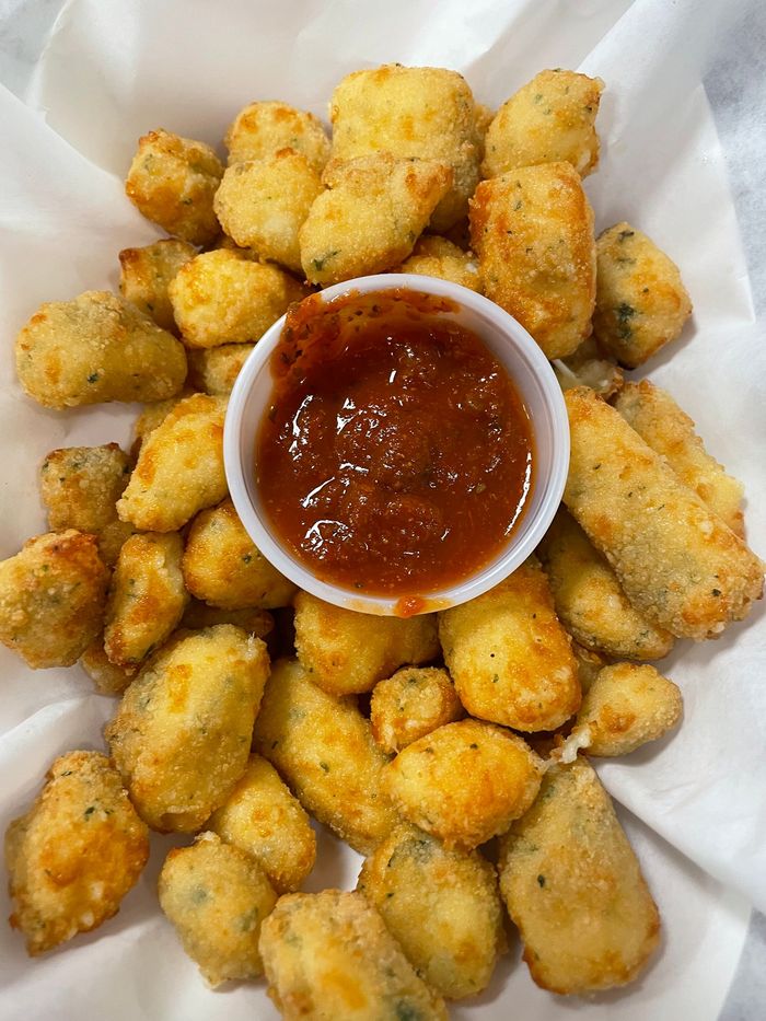 There is a small cup of ketchup on the side of the fried food.