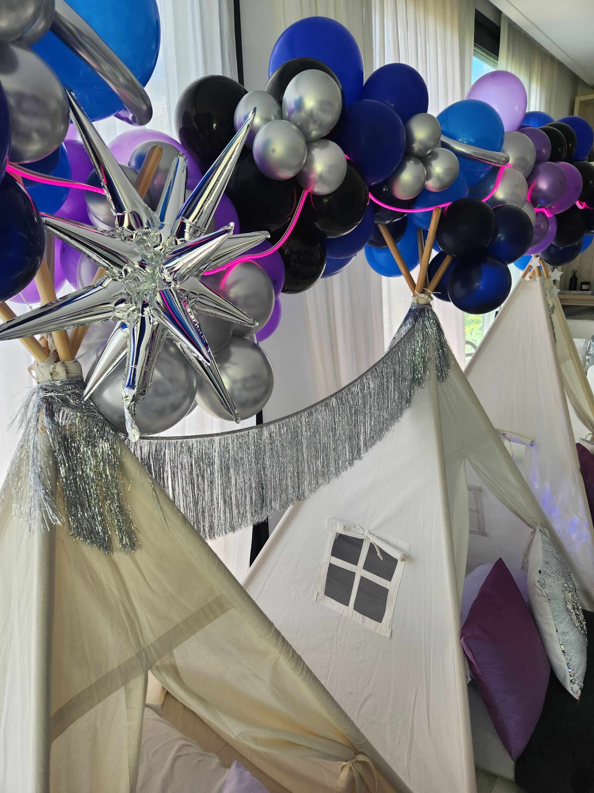 Tiendas tipi con decoración en forma de estrella y arco de globos en tonos azul, negro y plata.