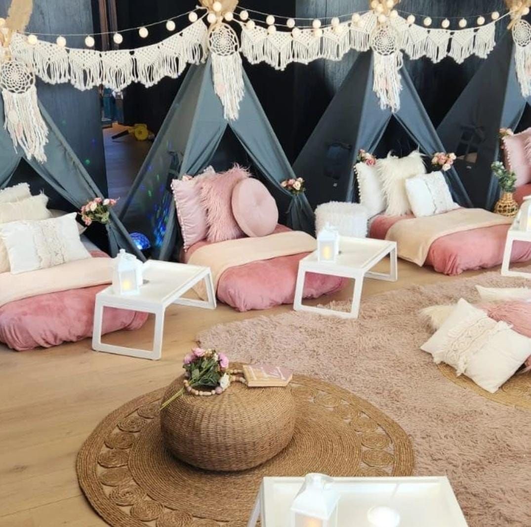 Pijamada en casa con temática rosa y crema. Tipis, almohadas, mantas y mesas pequeñas.