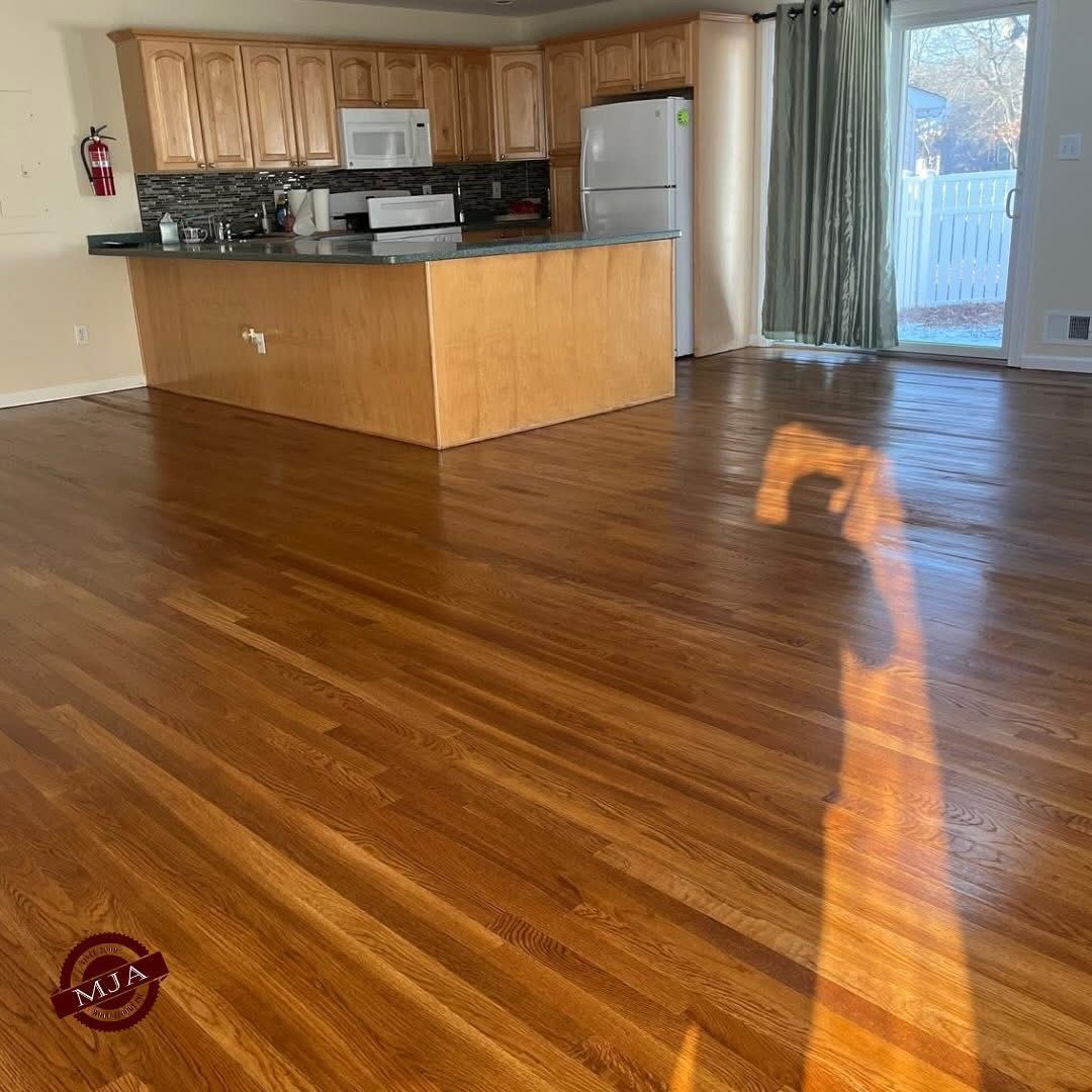 A view of a modern kitchen with light wood cabinets and a kitchen island, featuring hardwood floors.