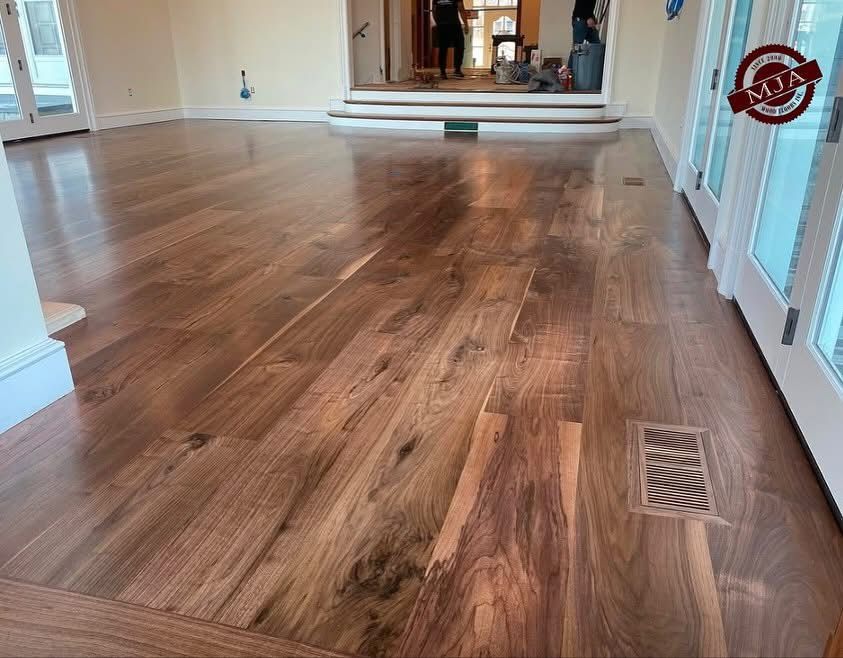 Newly installed, polished walnut hardwood flooring in a room with white trim and French doors leading to a raised area.