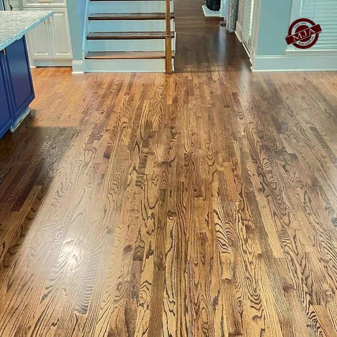 A room with polished, light-brown hardwood flooring extending toward wooden stairs and light-blue walls.