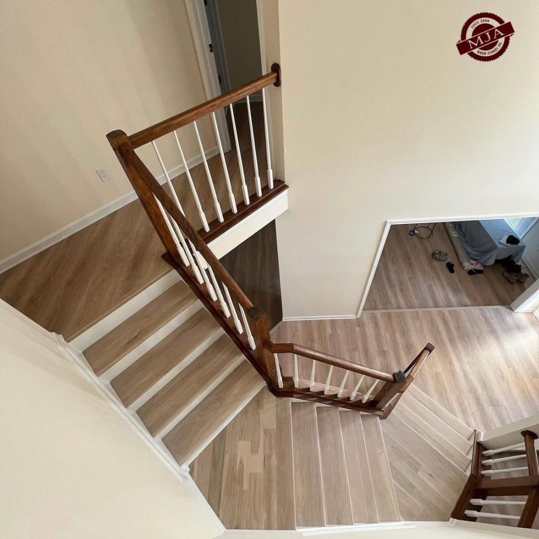 High-angle view of a wooden staircase with white balusters, connecting multiple levels of a modern home.