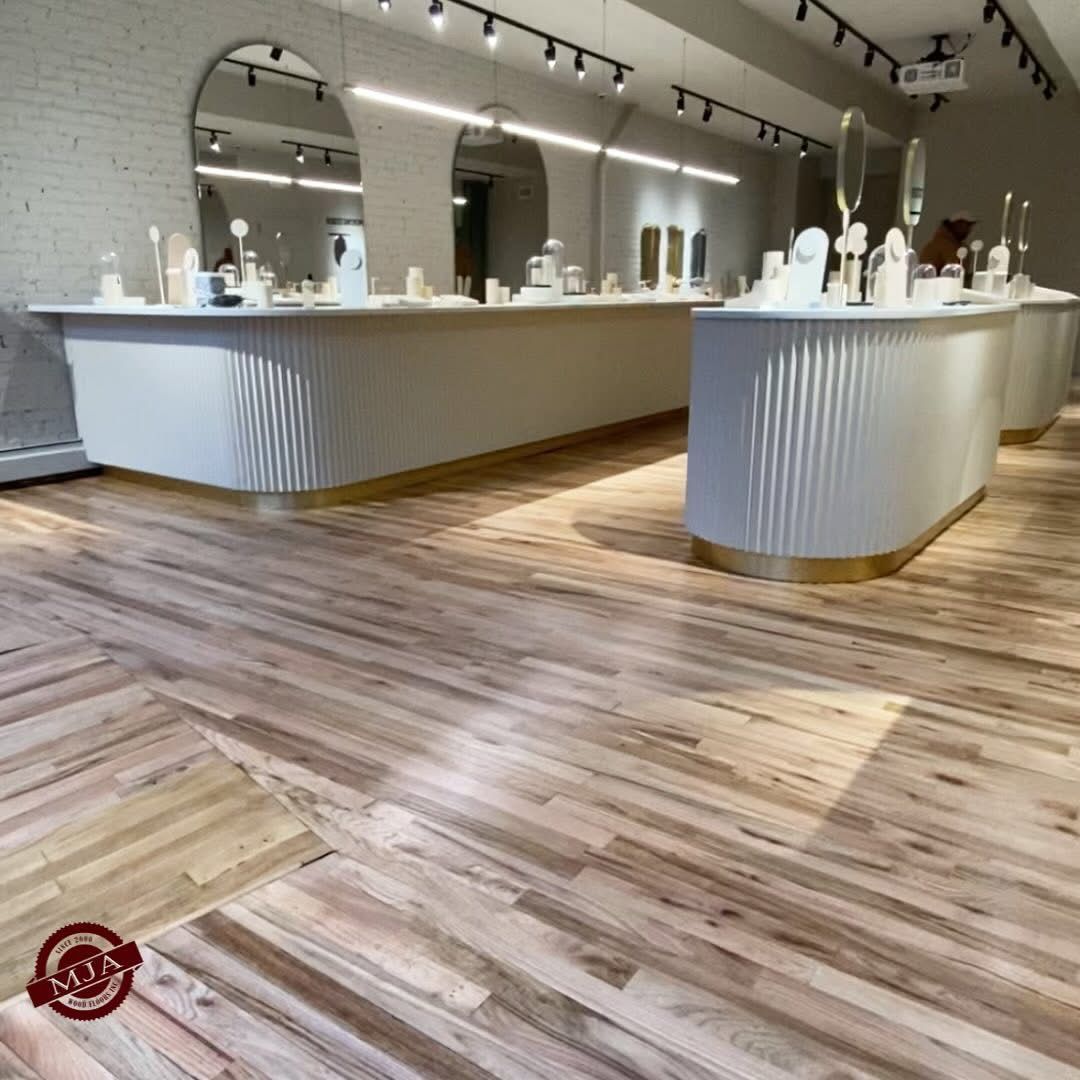 Modern retail jewelry store with white fluted counters, gold trim, wood flooring, and arched mirrors.