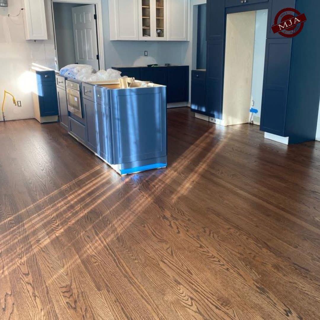 A kitchen interior features blue cabinets, a blue kitchen island, and dark stained hardwood floors under bright lighting.