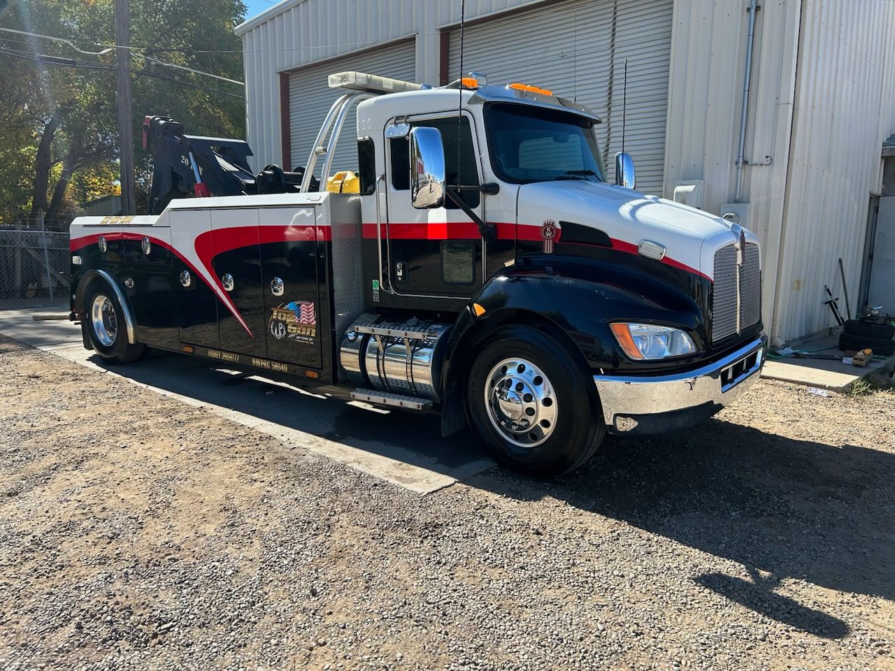 A black and white tow truck is parked in front of a building.