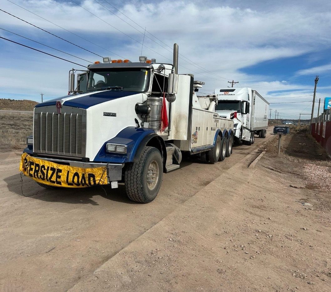 A tow truck is parked on the side of a dirt road.