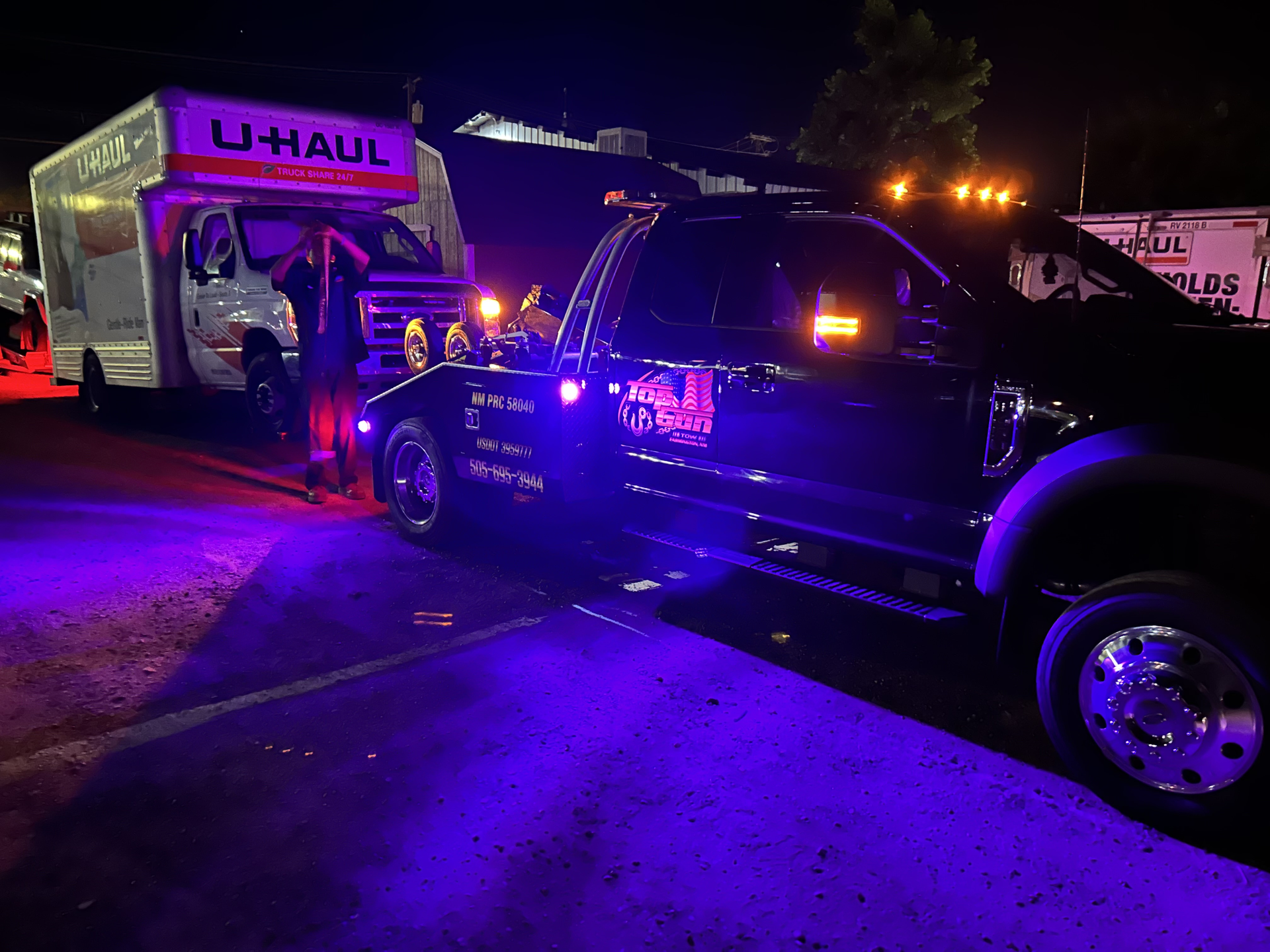 A truck is parked next to a u-haul truck at night.