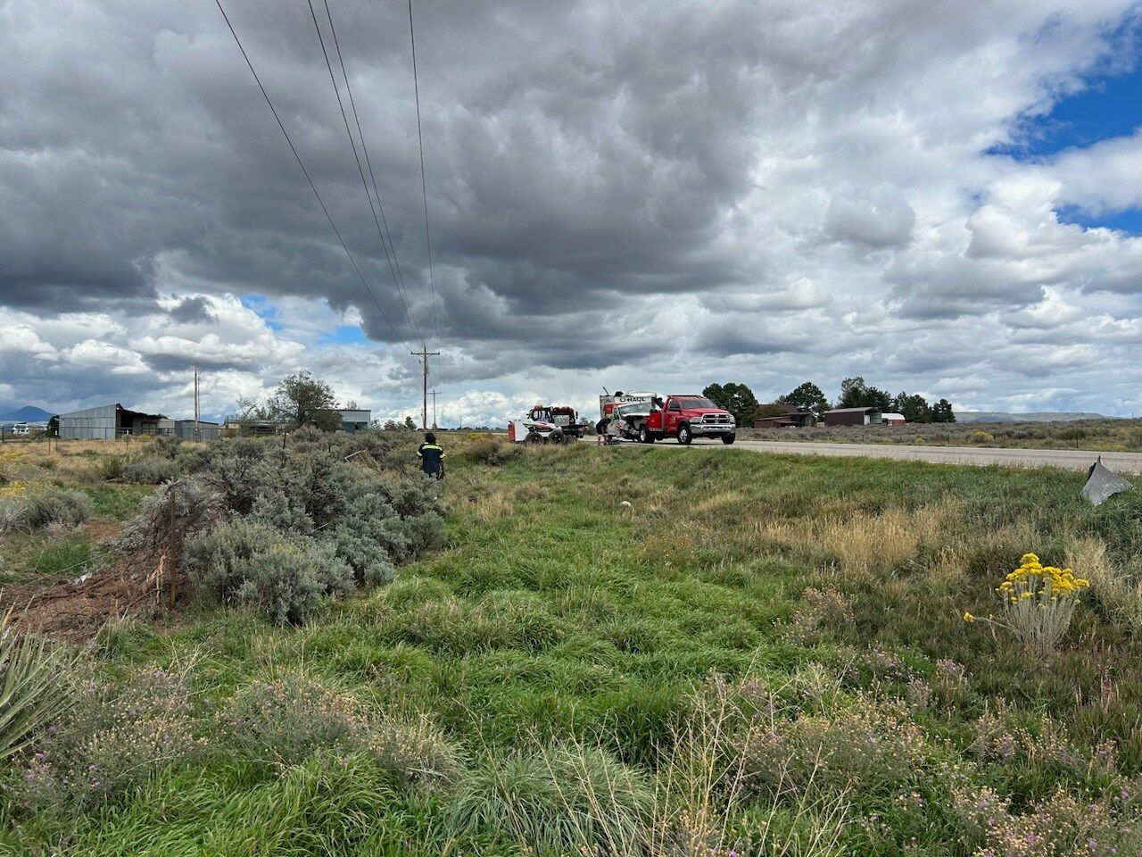 A red truck is parked on the side of the road in a grassy field.