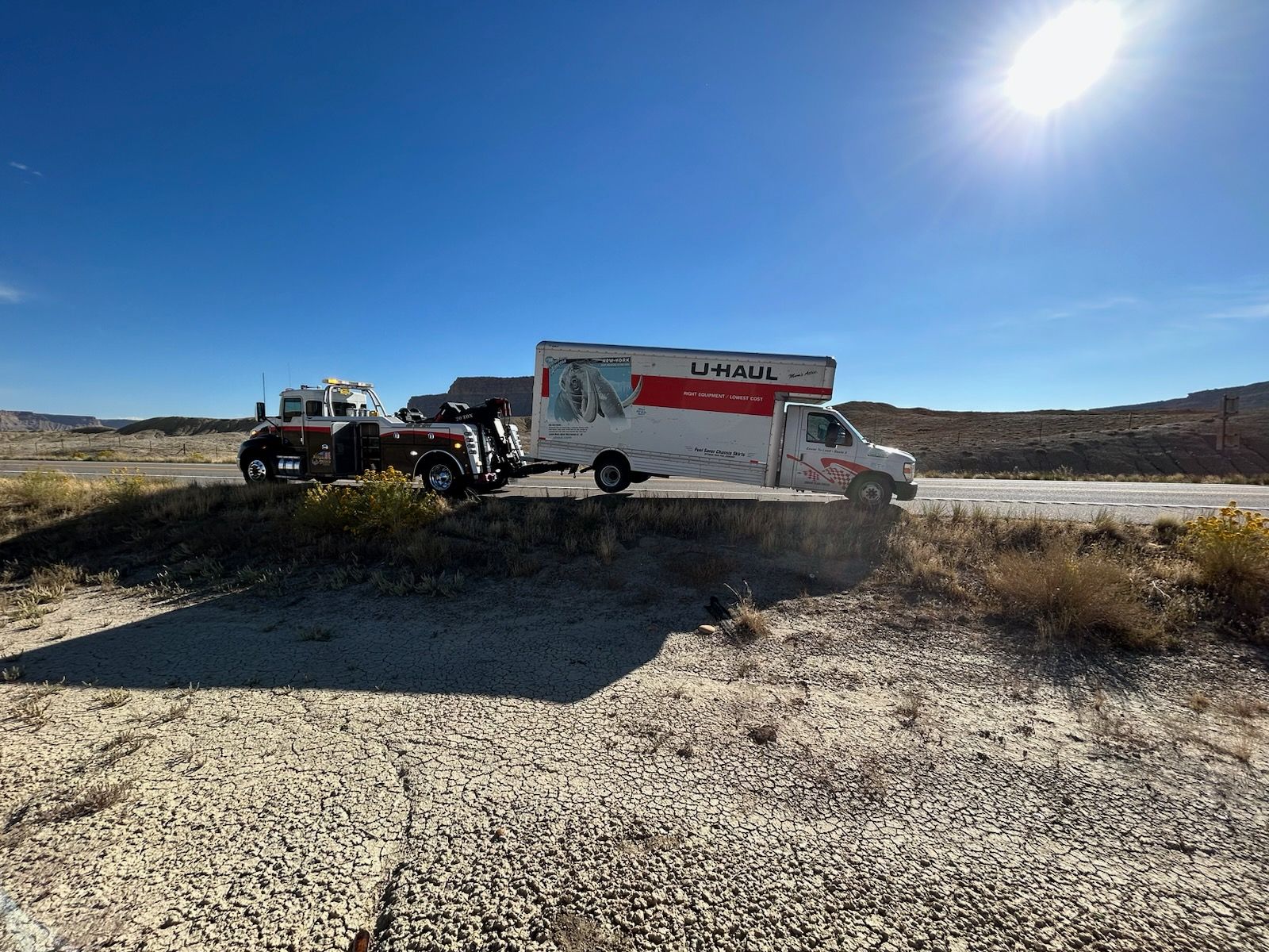 A truck is towing a trailer on the side of the road.