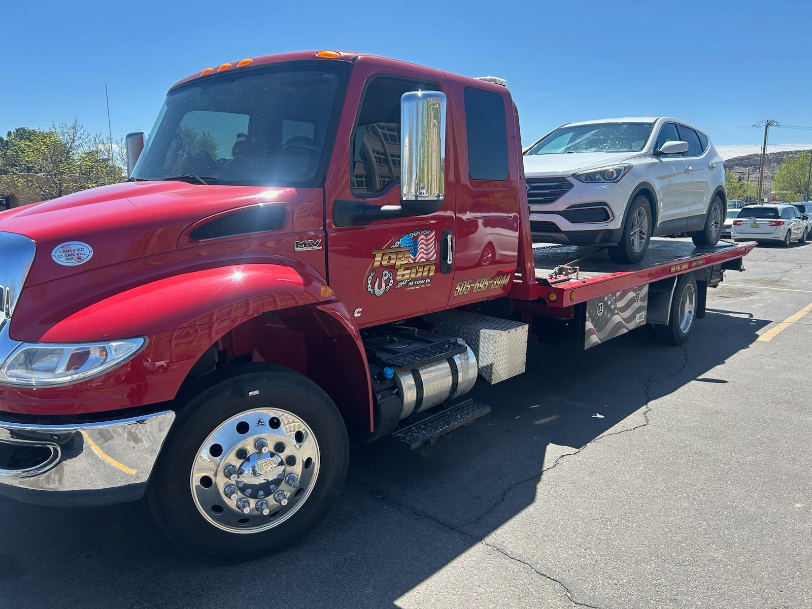 A red tow truck with a white suv on the back is parked in a parking lot.