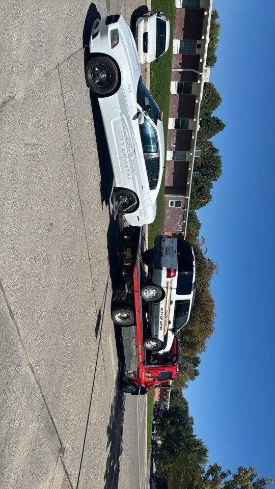 A white car is being towed by a tow truck.