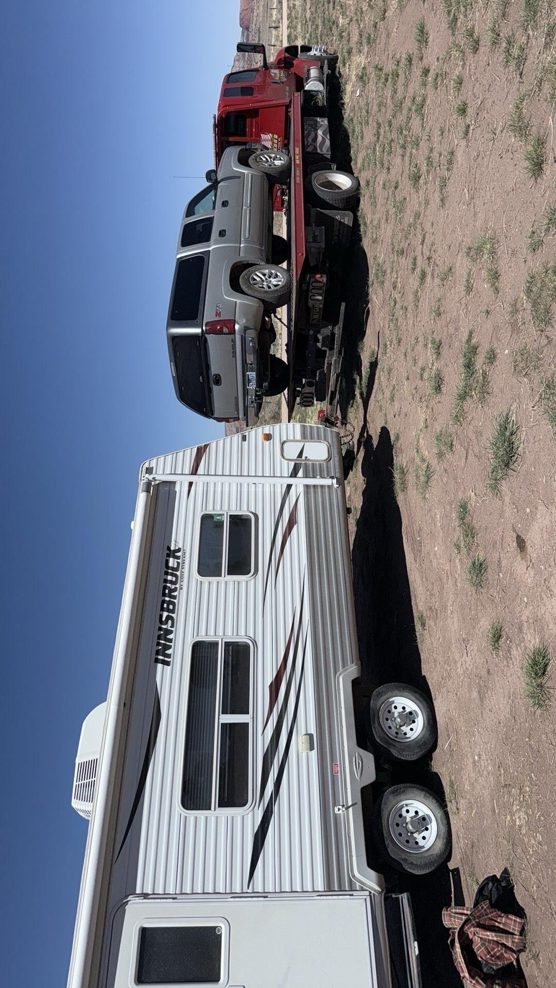 A tow truck is towing a trailer with a car on it.