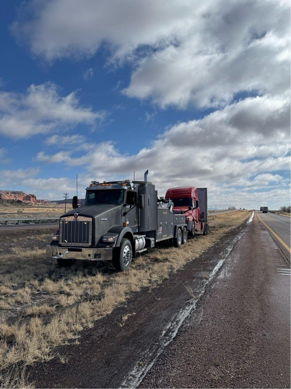 Two semi trucks are parked on the side of the road