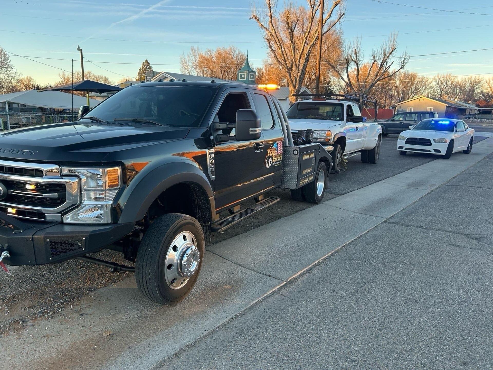 A tow truck is parked on the side of the road next to a police car.