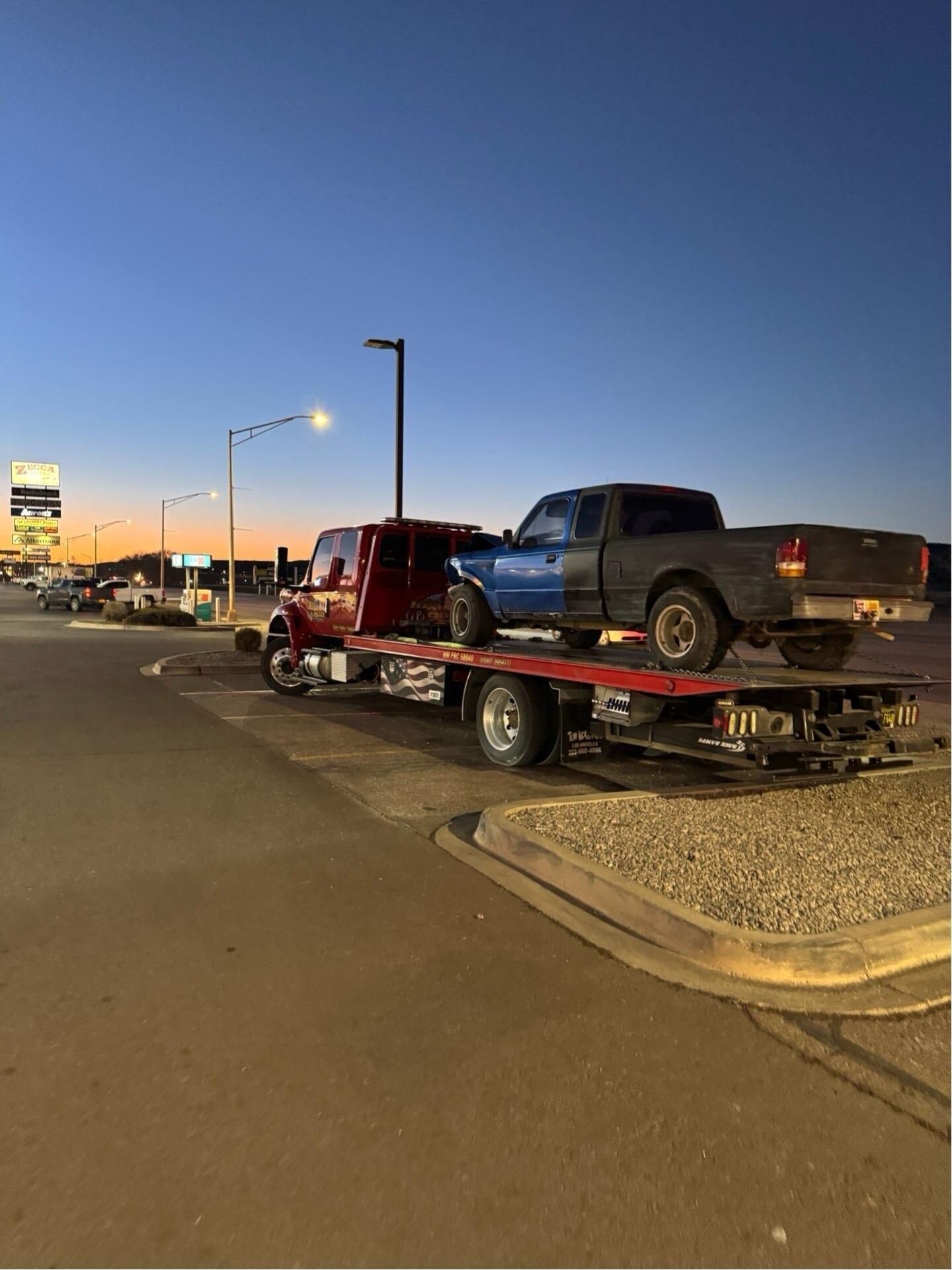 A tow truck is towing a blue truck and a red truck.